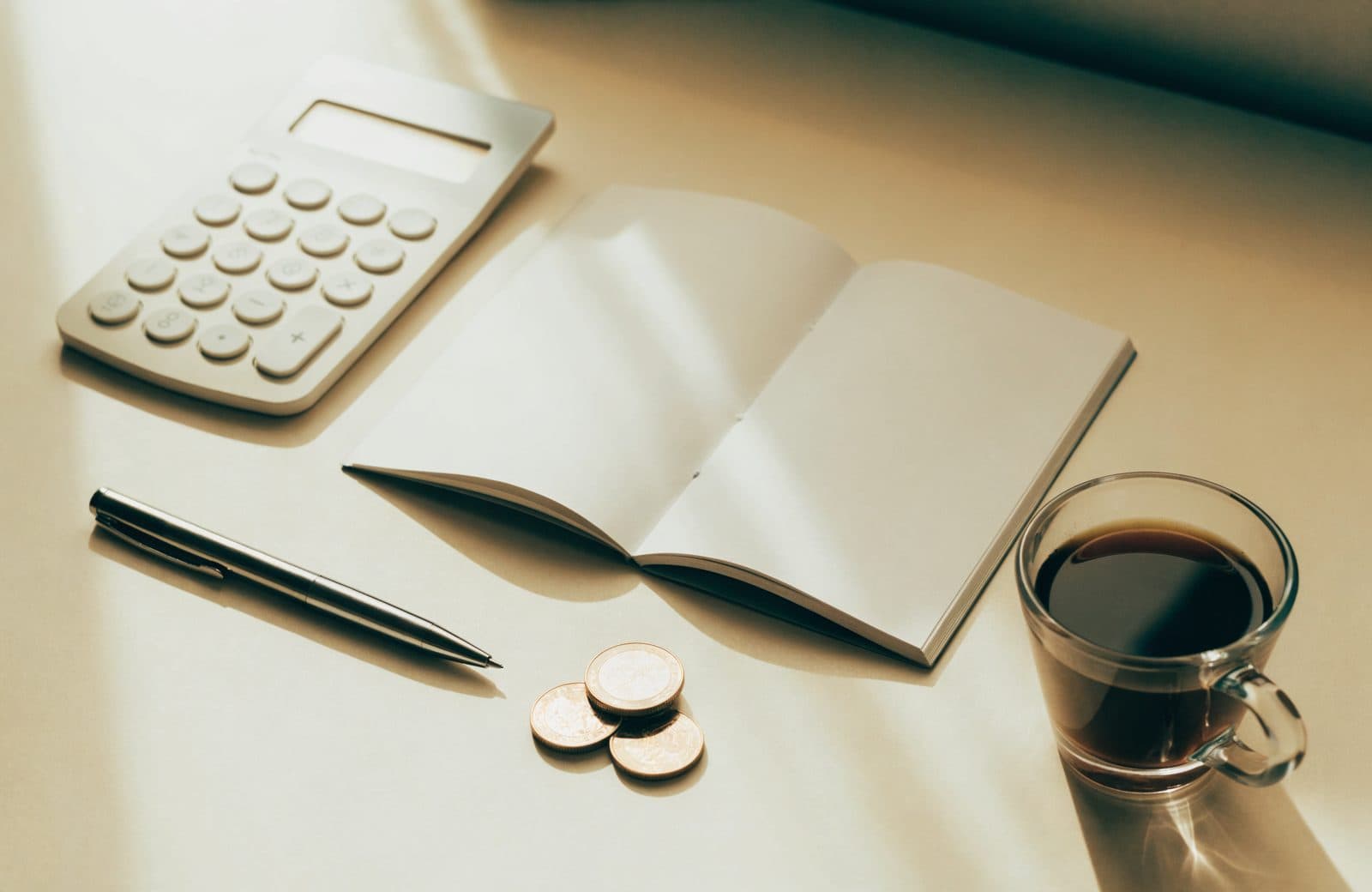 Mesa com calculadora, caderno, moedas e café — organização financeira