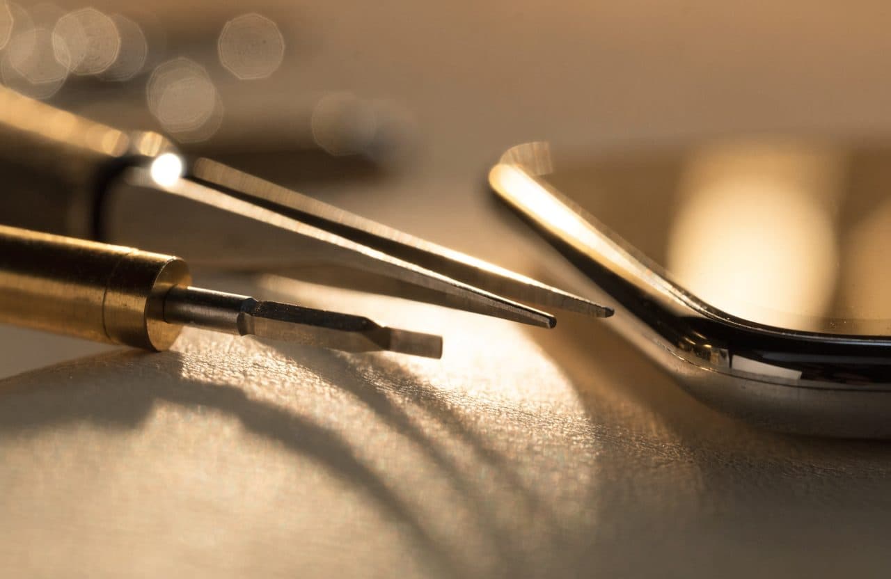 Close-up de ferramentas de precisão douradas ao lado de um smartphone